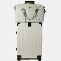 White travel bag with front pockets, top handle, and four rolling wheels