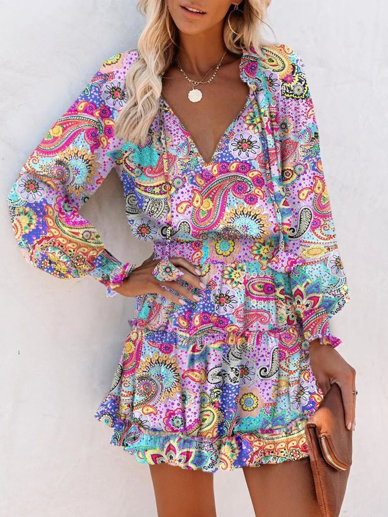Tie-neck lantern sleeve dress in colorful paisley print with ruffled hem and elastic waist.