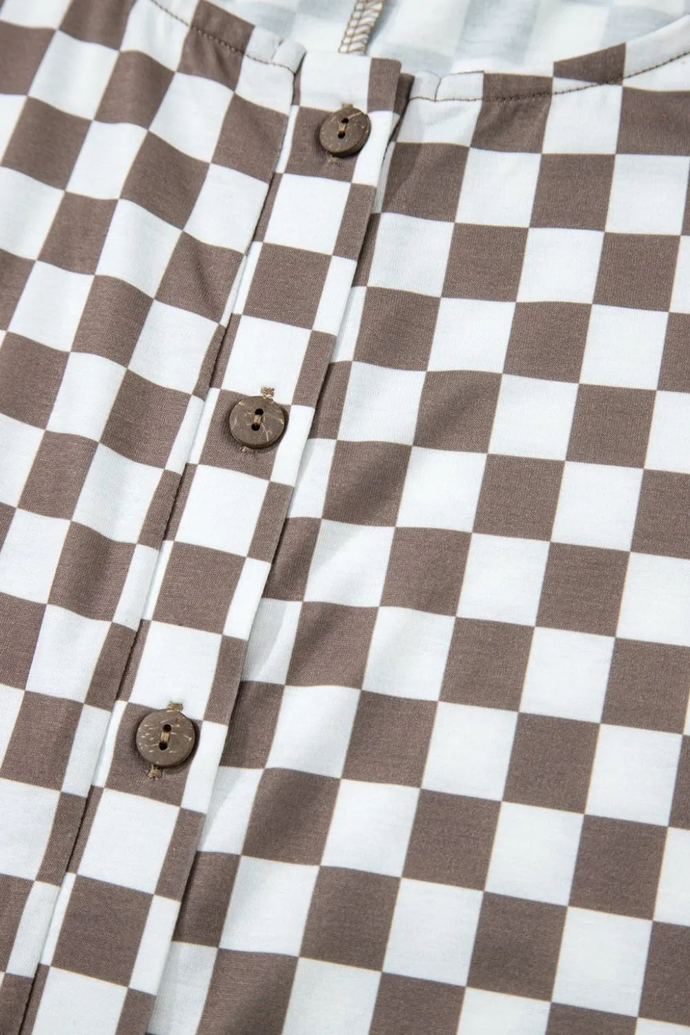 Brown-and-white checkered jumpsuit front placket with round button closures