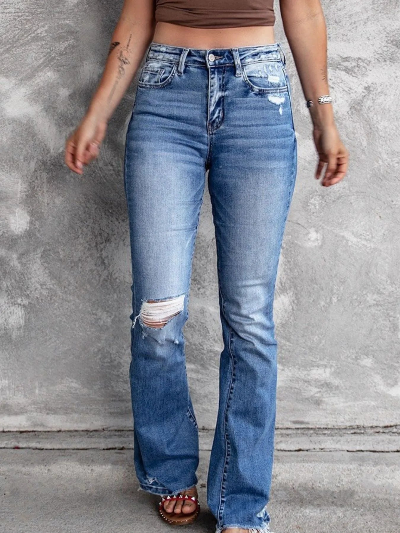 Light blue distressed flare jeans with ripped knee panels and a mid-rise button waist