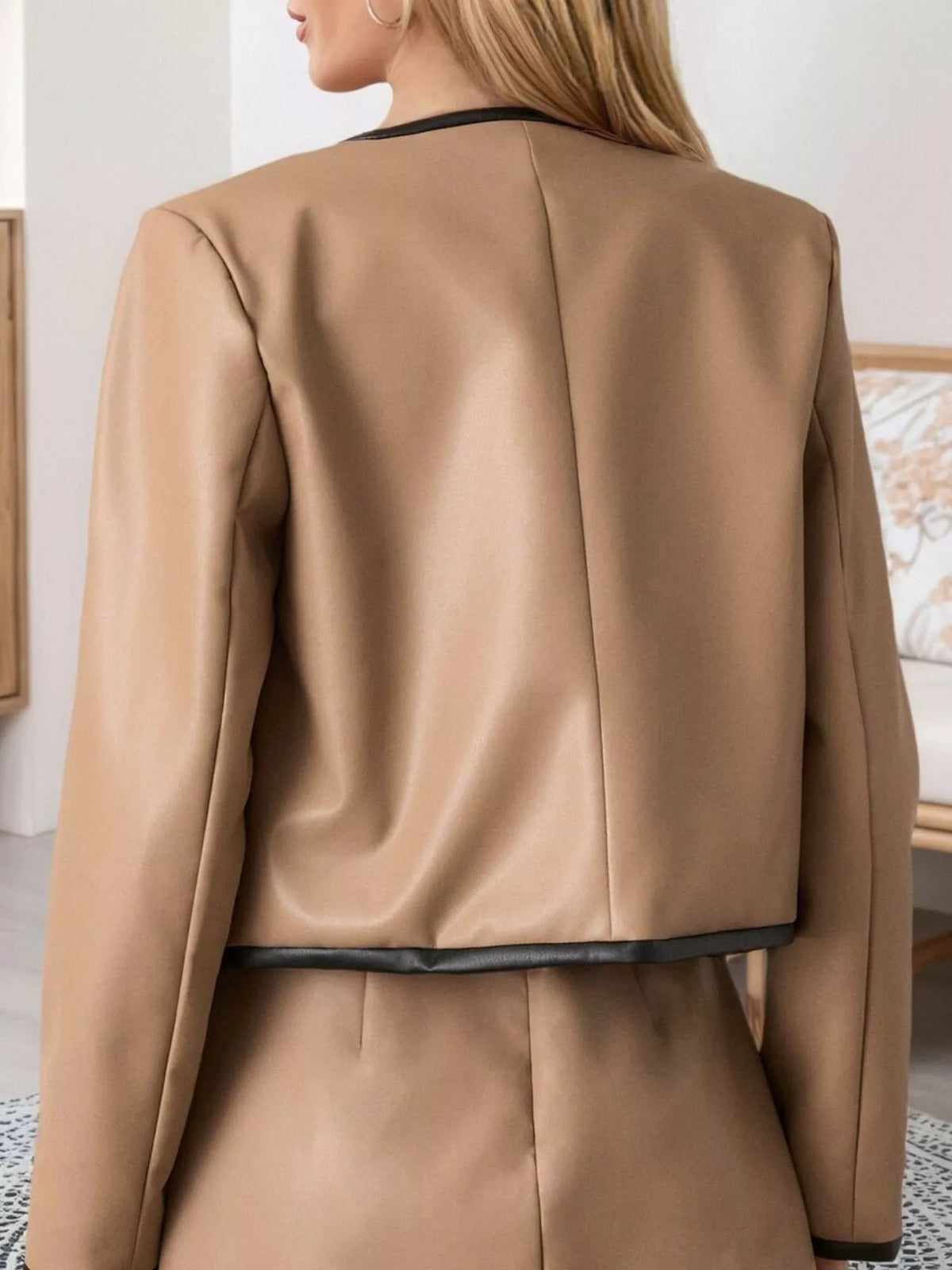Tan jacket back with black waistband trim and seamed silhouette