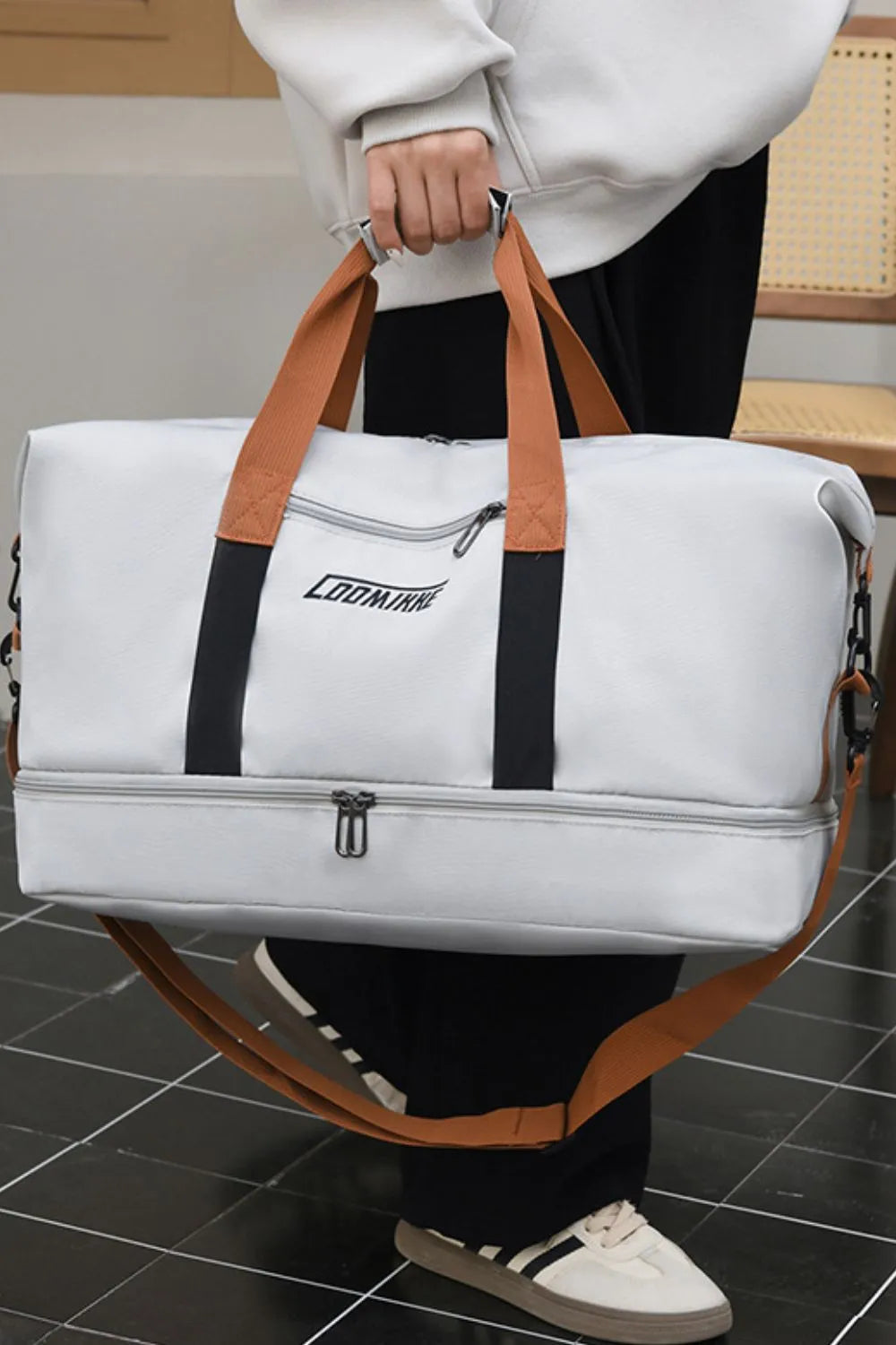 Light gray waterproof travel duffel with brown handles and central zip divider