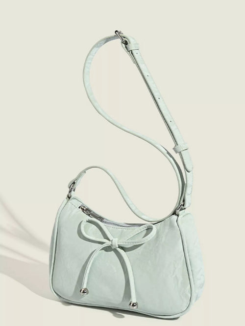 Light green bow-accent shoulder bag with crescent profile and adjustable shoulder strap
