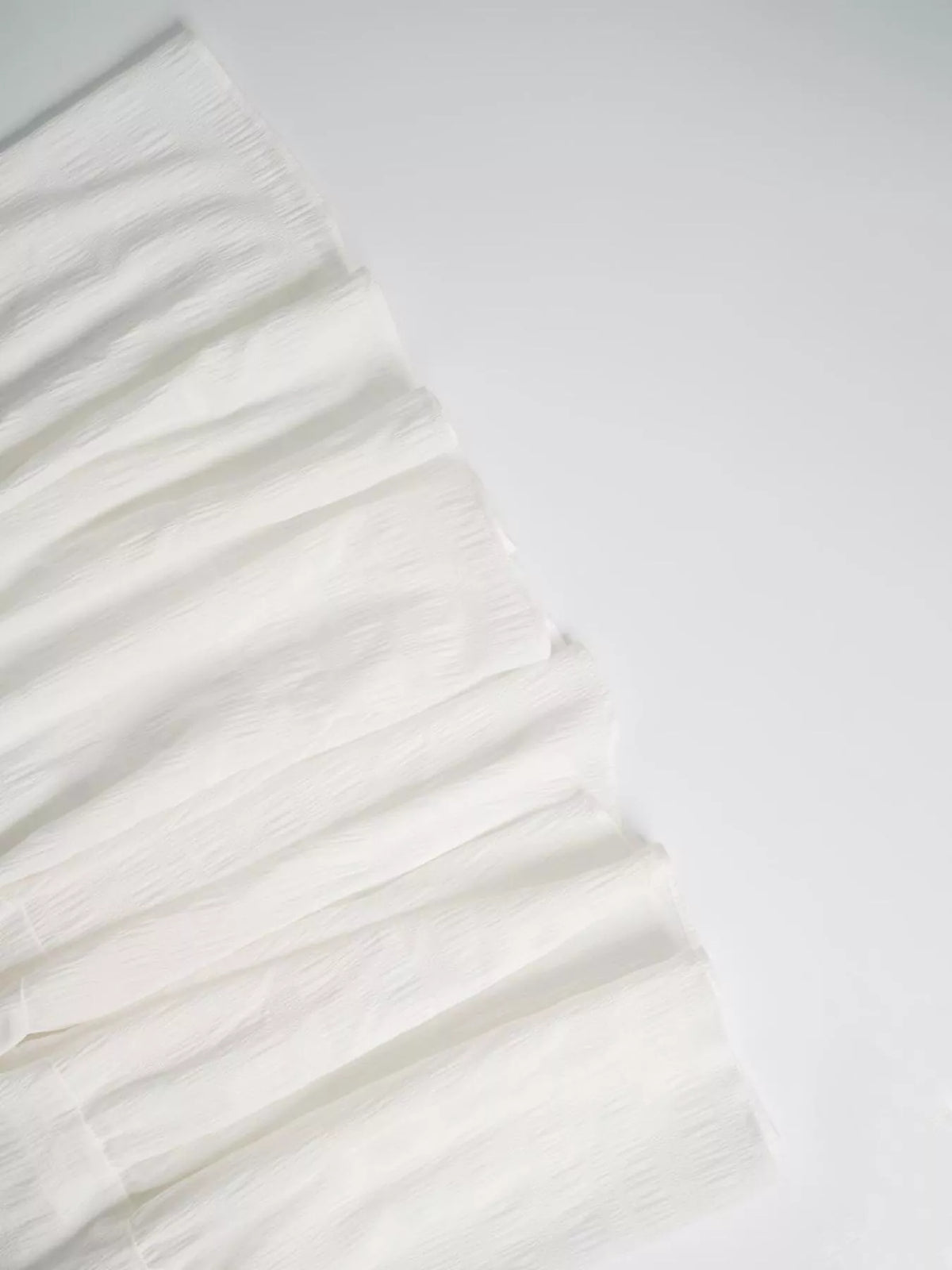 White ruffle-tier fabric close-up with gathered pleats and soft crinkled texture