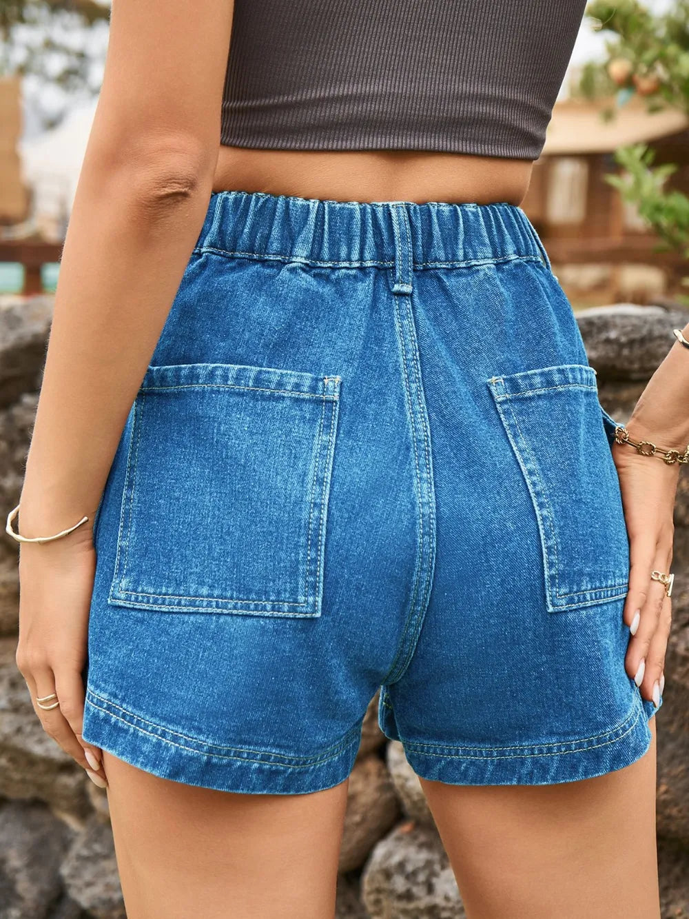 High-waist medium blue denim shorts with button closure, belt loops, and side pockets