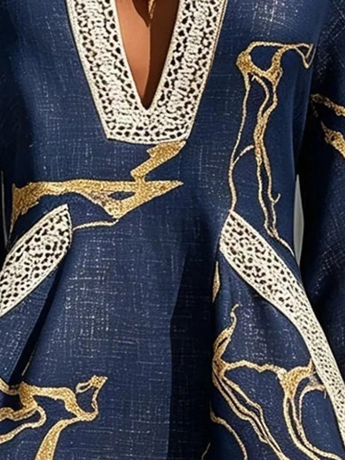 Navy mini dress close-up of V-neck lace trim and gold patterned detailing