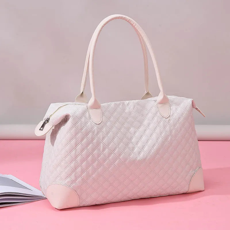 Dusty pink quilted travel bag with top handles, side pulls, and zip closure