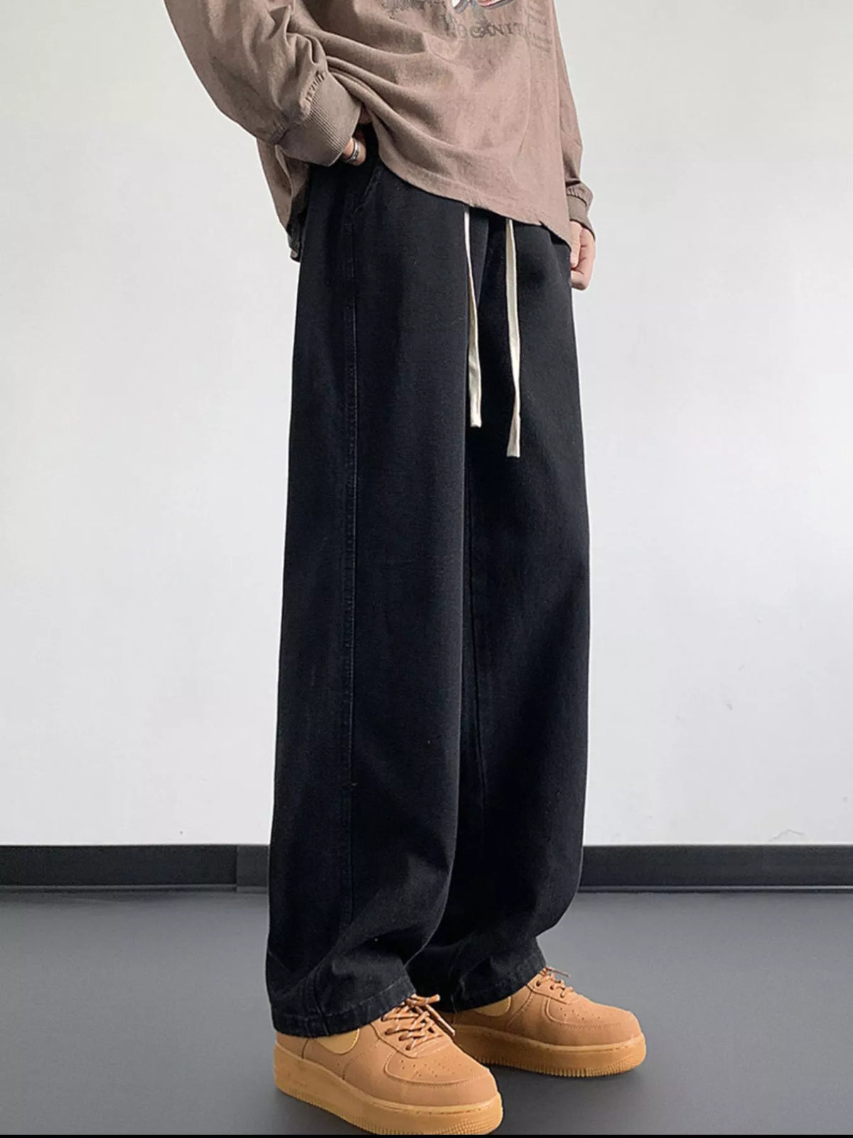 Black washed denim jeans with loose fit, wide legs, and long drawstring ties
