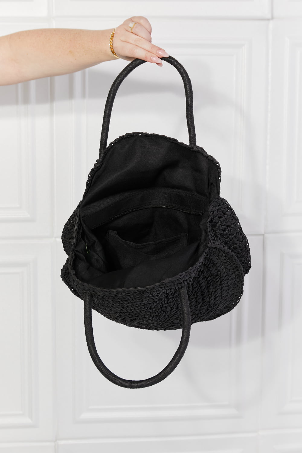 Black round woven straw rattan handbag with open top and black fabric lining