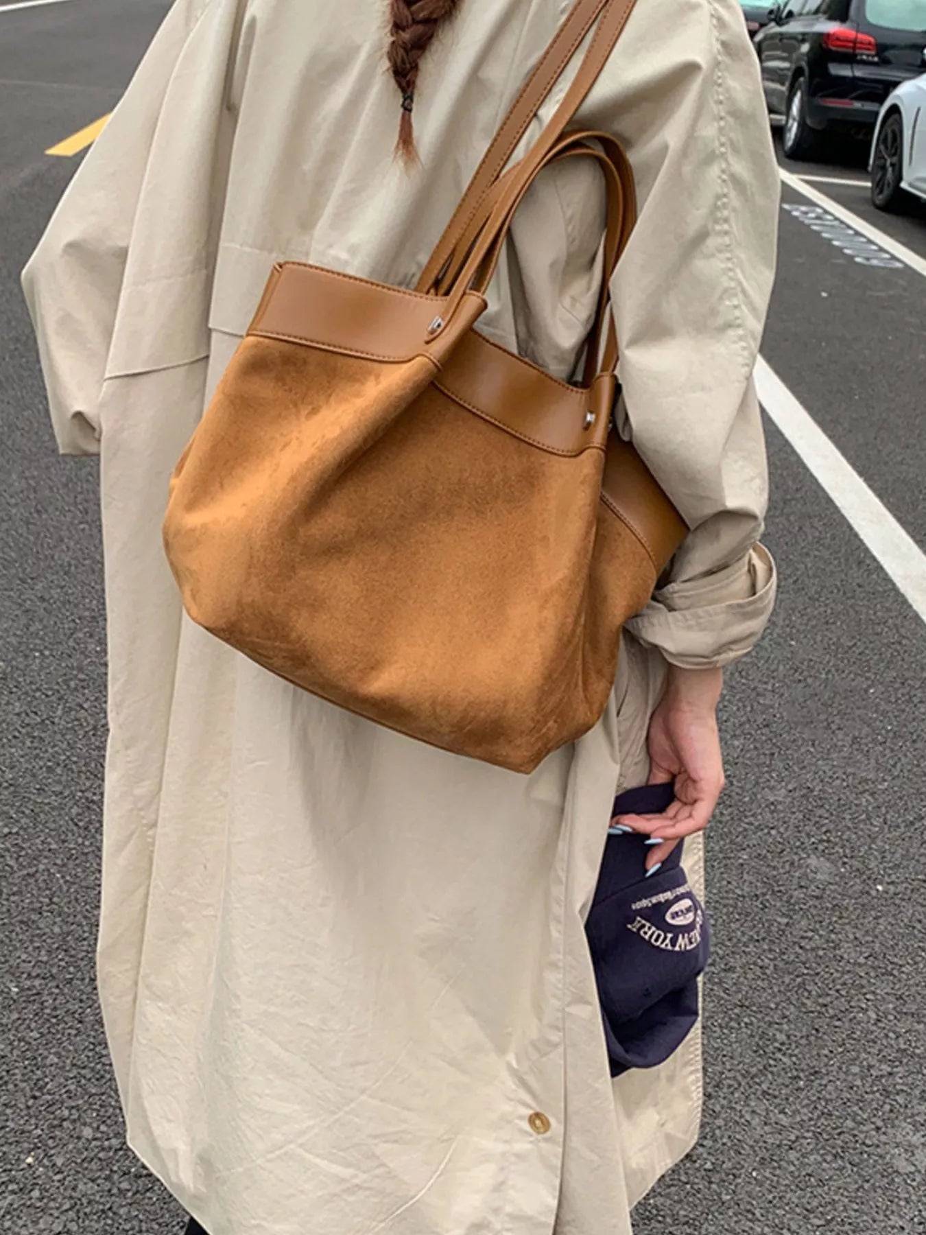 Brown suede shoulder bag with wide leather straps and rounded bottom