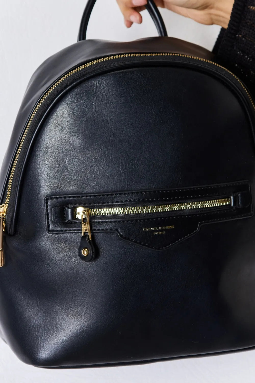 Black vegan leather mini backpack close-up of front zip pocket and gold zipper pull