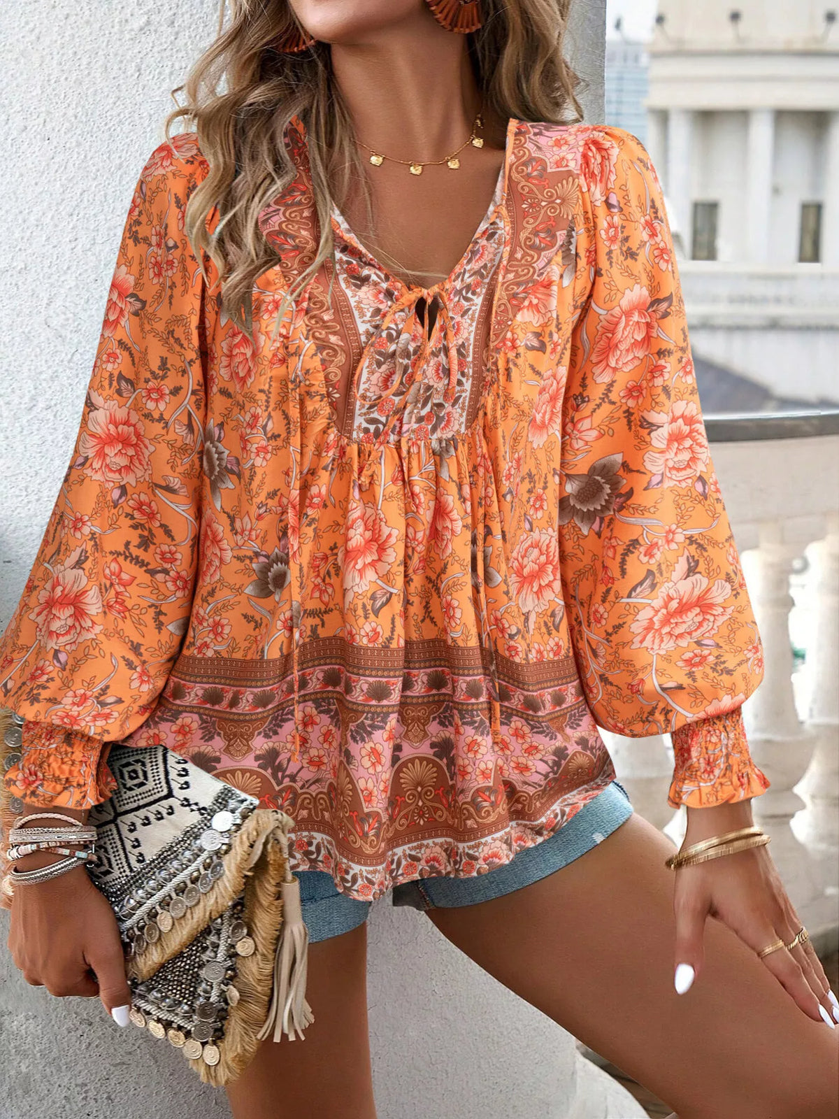 Orange floral tie-neck blouse with smocked cuffs and decorative border hem