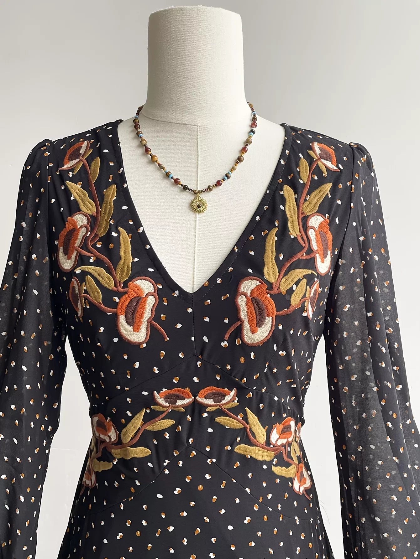 Black floral-embroidered bodice with V neckline and long sheer polka dot sleeves