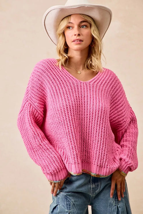Women’s pink V-neck knit sweater with ribbed cuffs and hem; colorful trim at bottom.