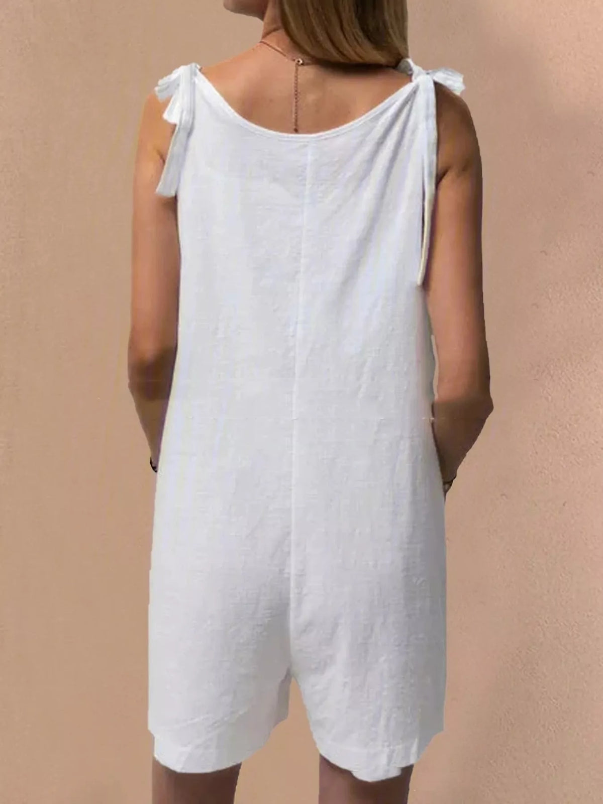 White tie-shoulder bow romper with back bow straps and pockets, mid-waist.