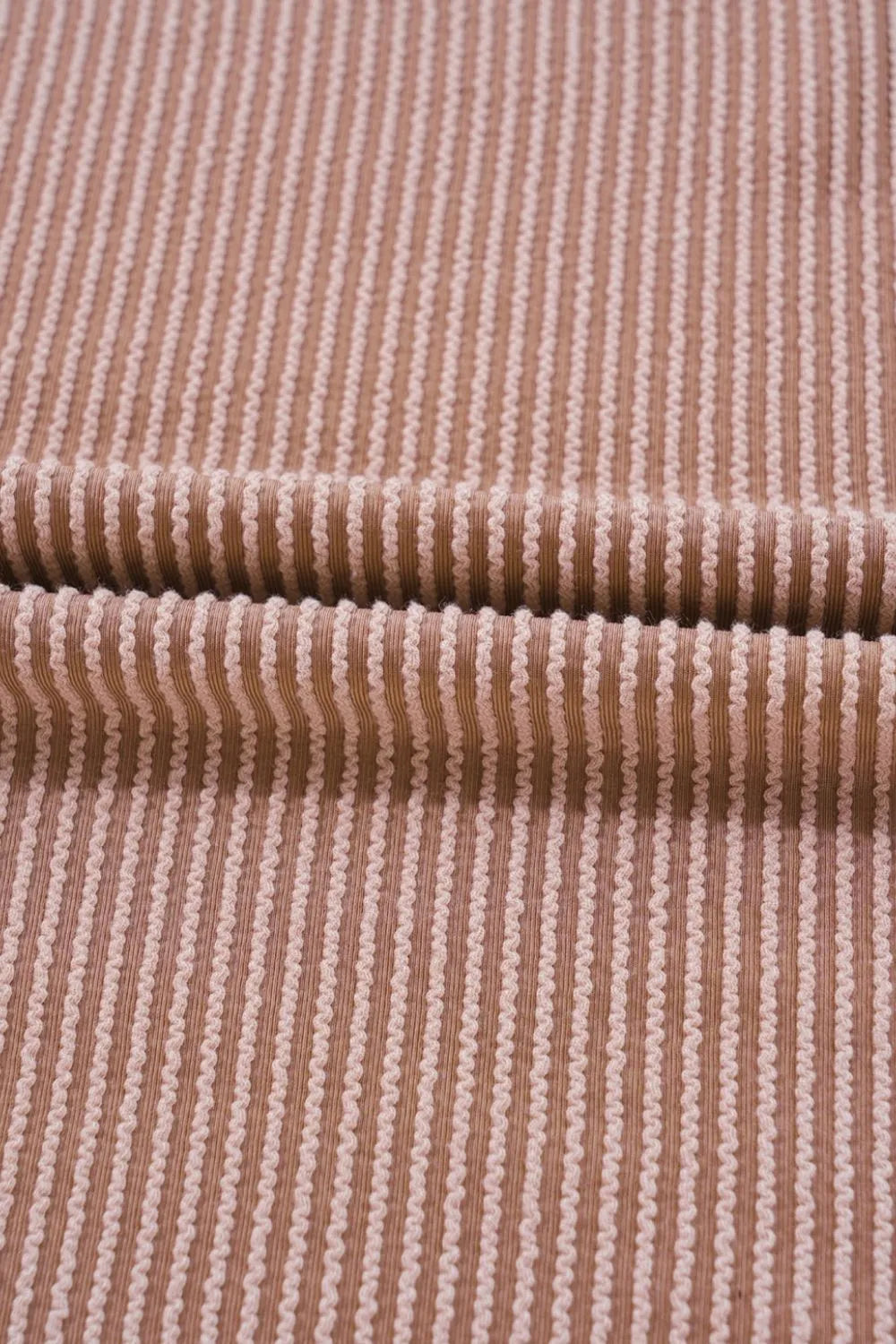 Close-up of dusty mauve corded fabric with fine vertical stripe texture