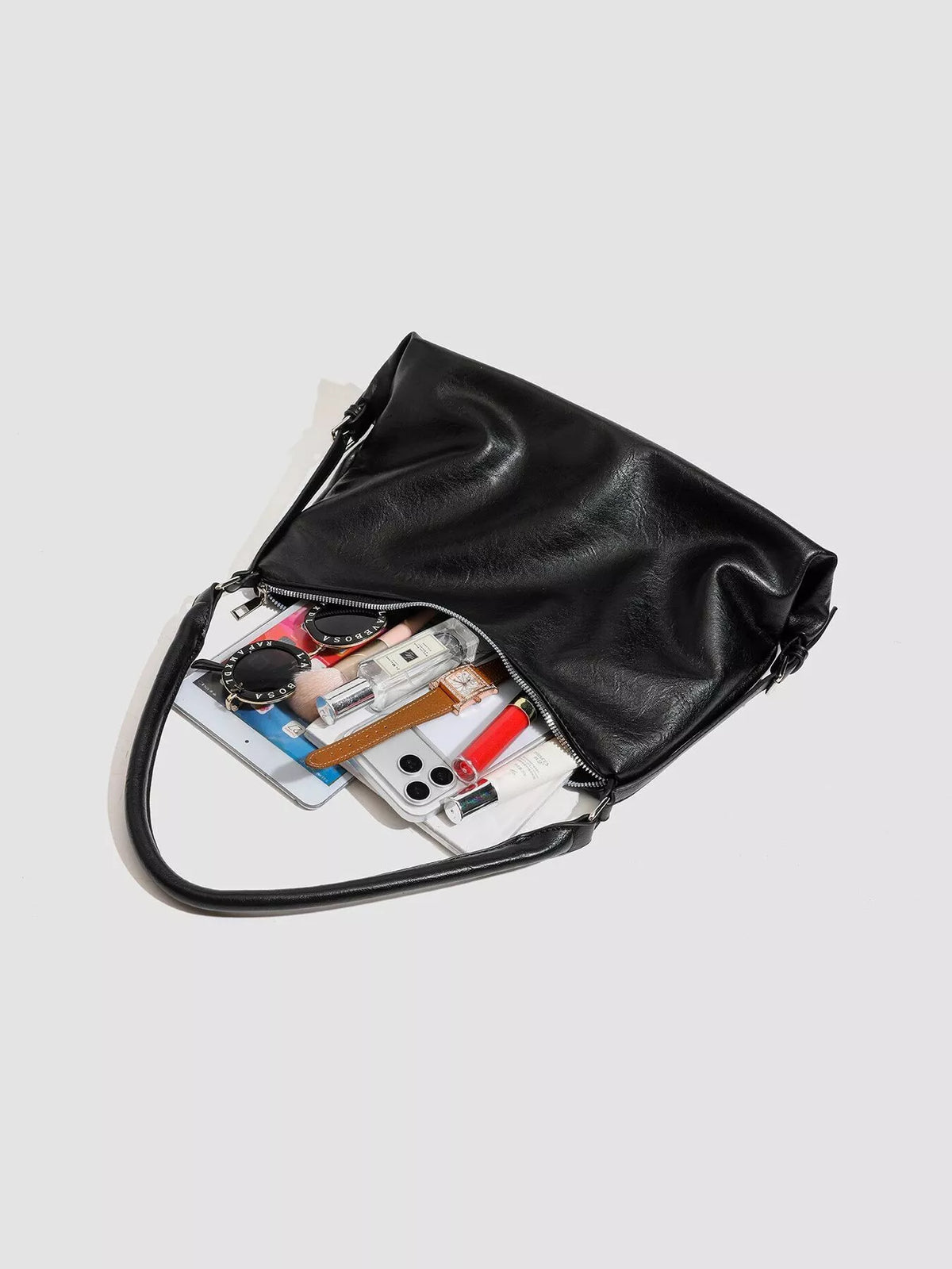 Black vegan leather shoulder bag open with top zip, showing interior pockets