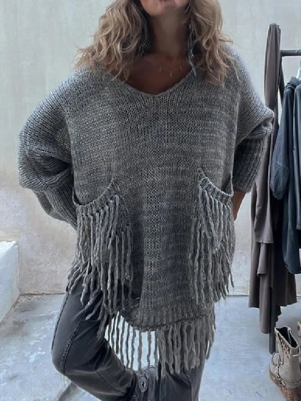 Dark gray long-sleeve sweater with fringe pocket openings and soft knit texture.