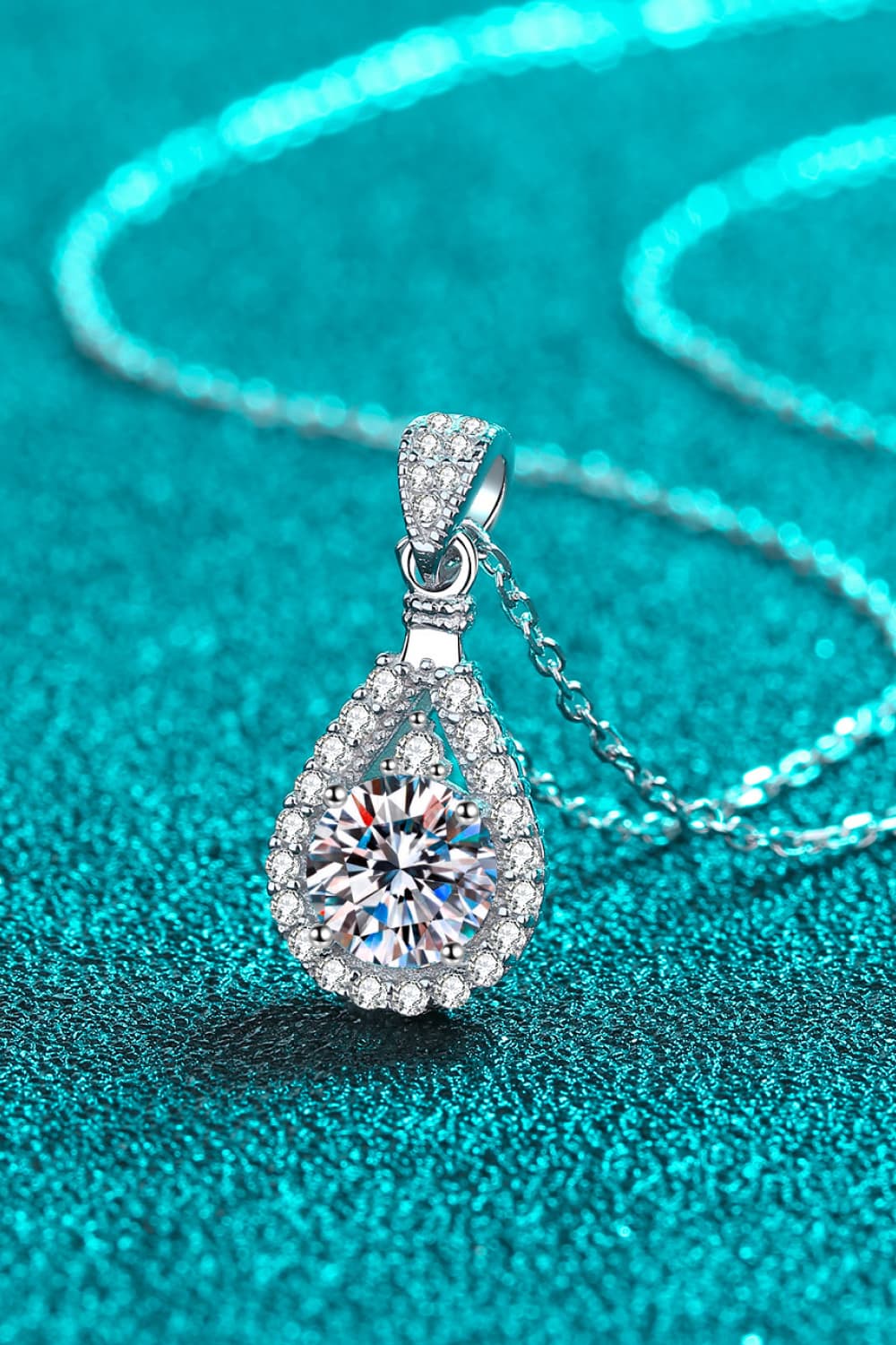 Sterling silver moissanite teardrop pendant with pavé halo, close-up on chain