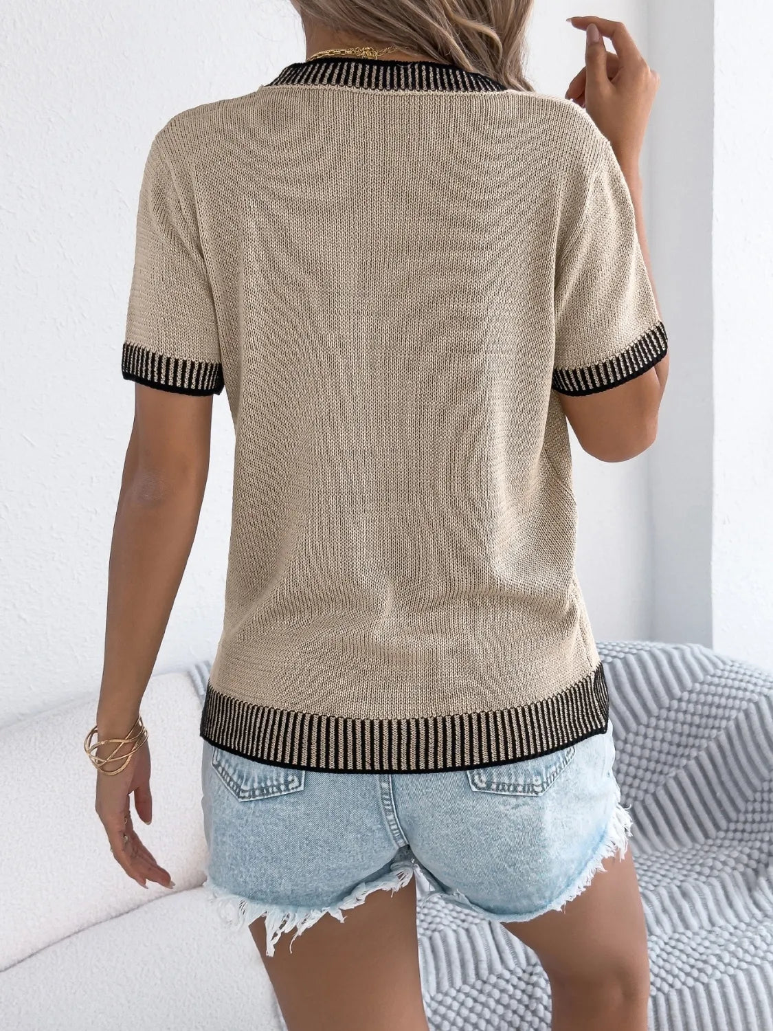 Back view of round-neck short-sleeve knit top in light tan with striped cuffs and hem trim.