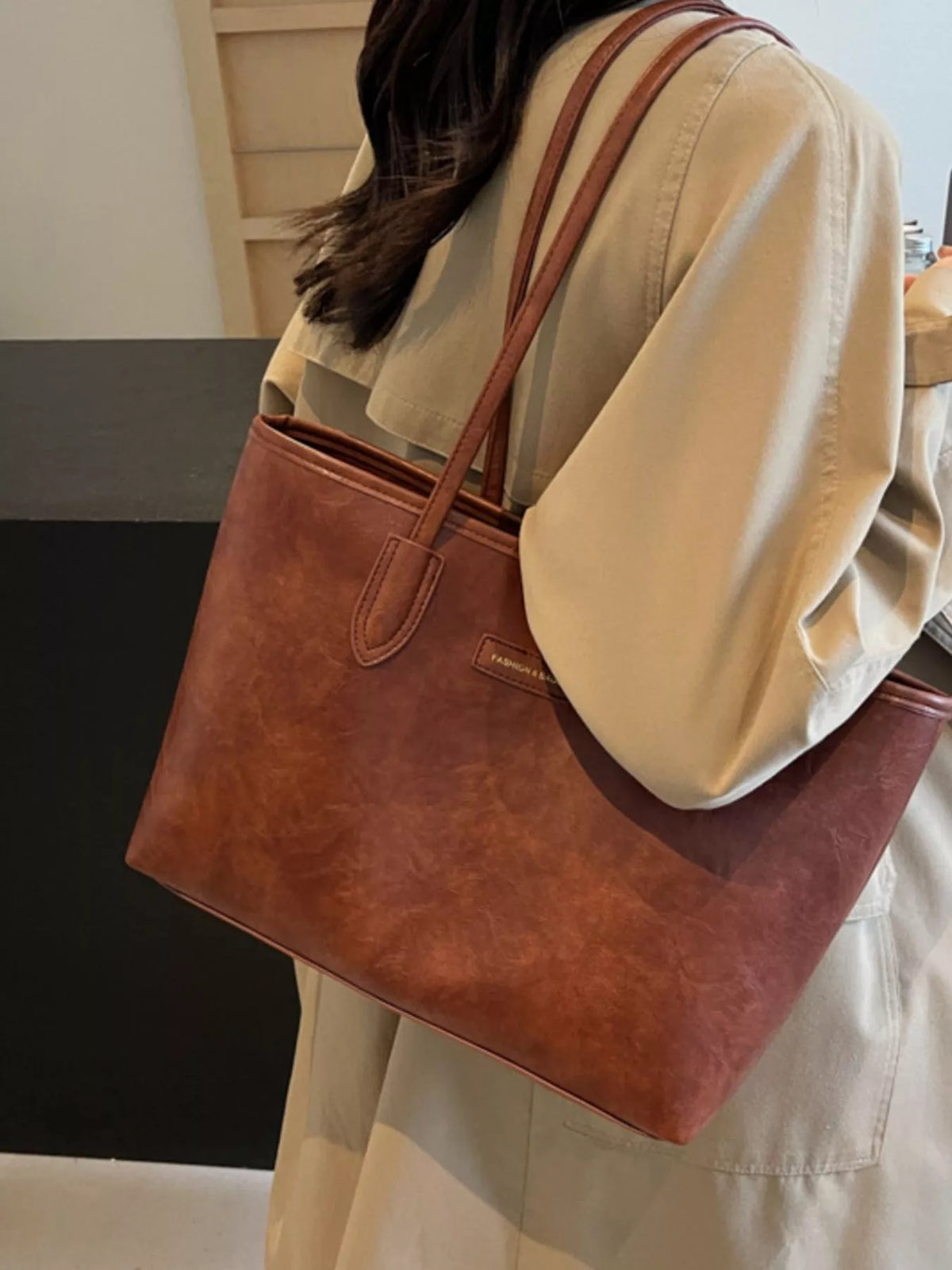 Brown vegan leather tote bag with double handles and stitched front pocket