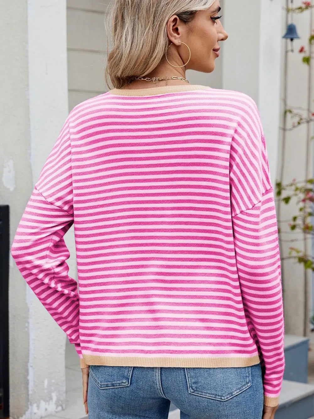 Back view of hot pink and white striped round-neck long-sleeve sweater with cream trim