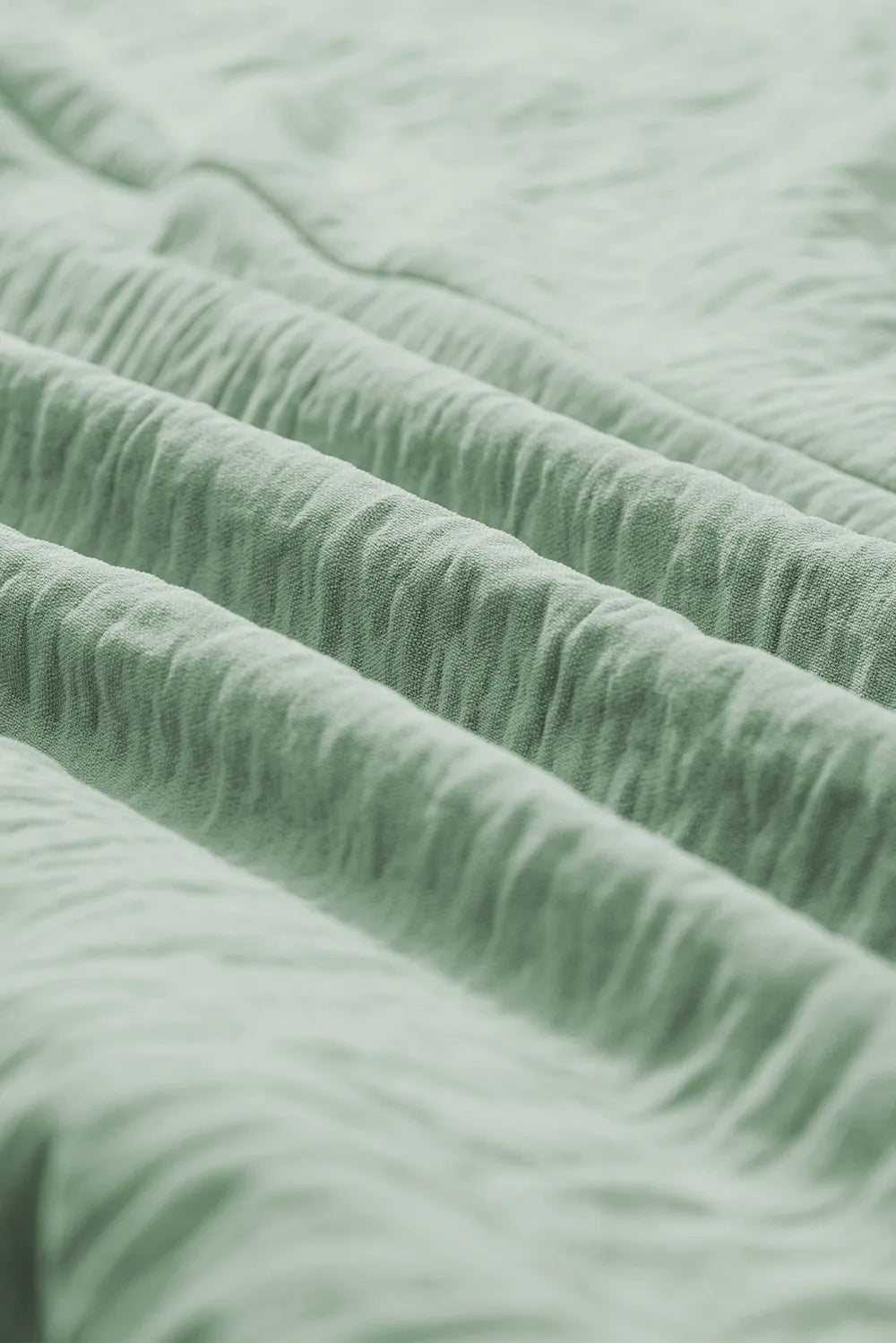 Sage green crinkled fabric detail with stitched seam