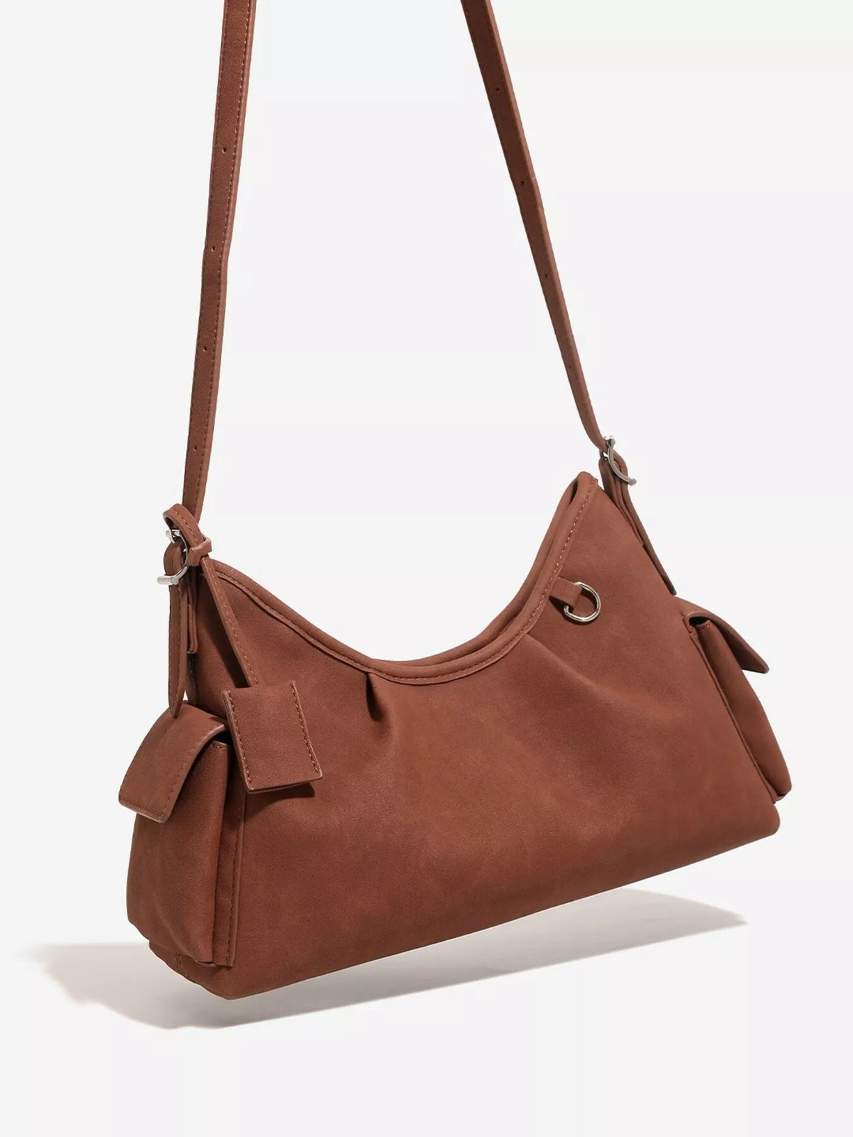 Brown suede shoulder bag with ruched opening, adjustable strap, and side tie accents