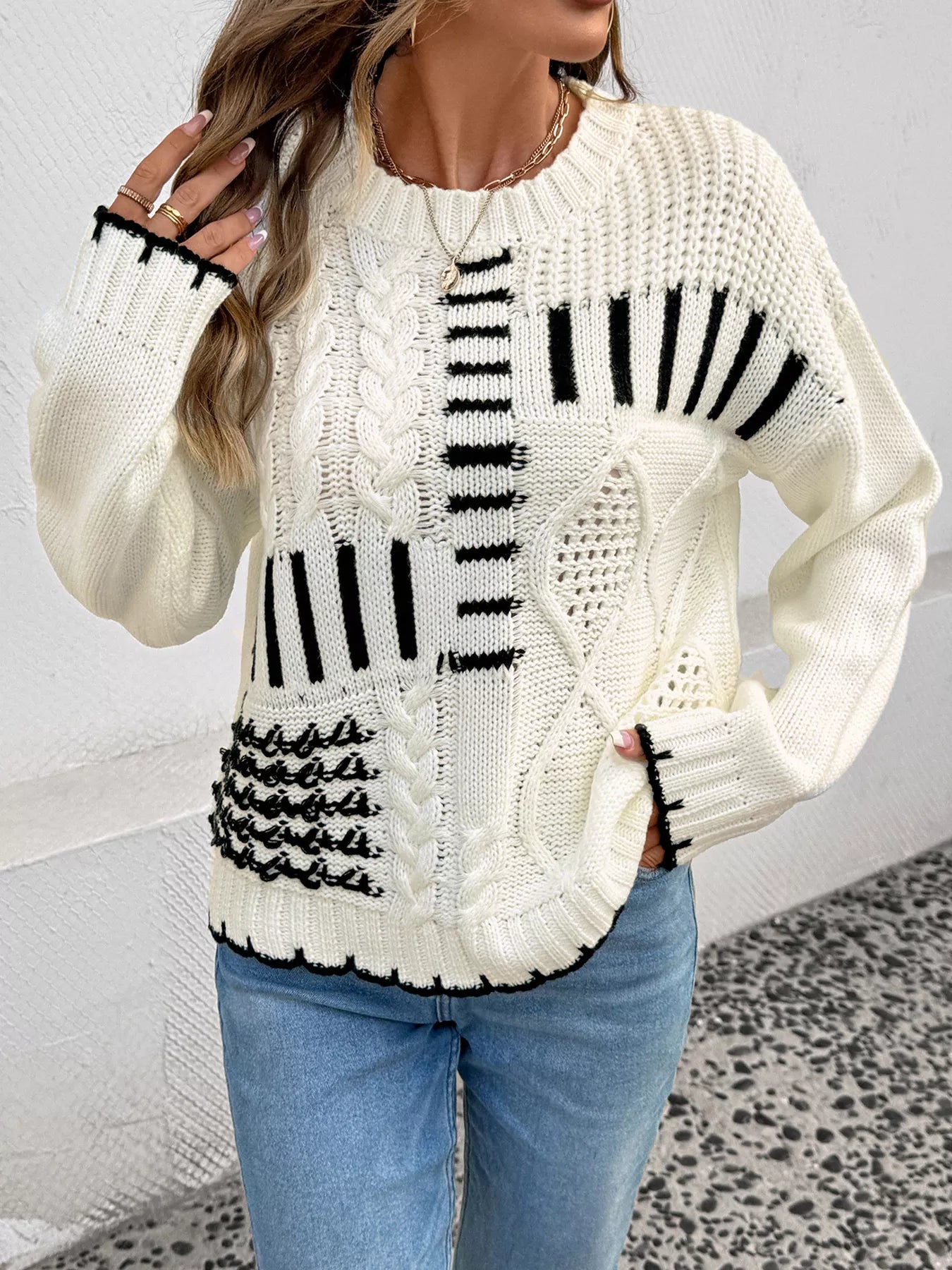 Ivory cable knit round-neck sweater with black stripe graphic and textured cable panels
