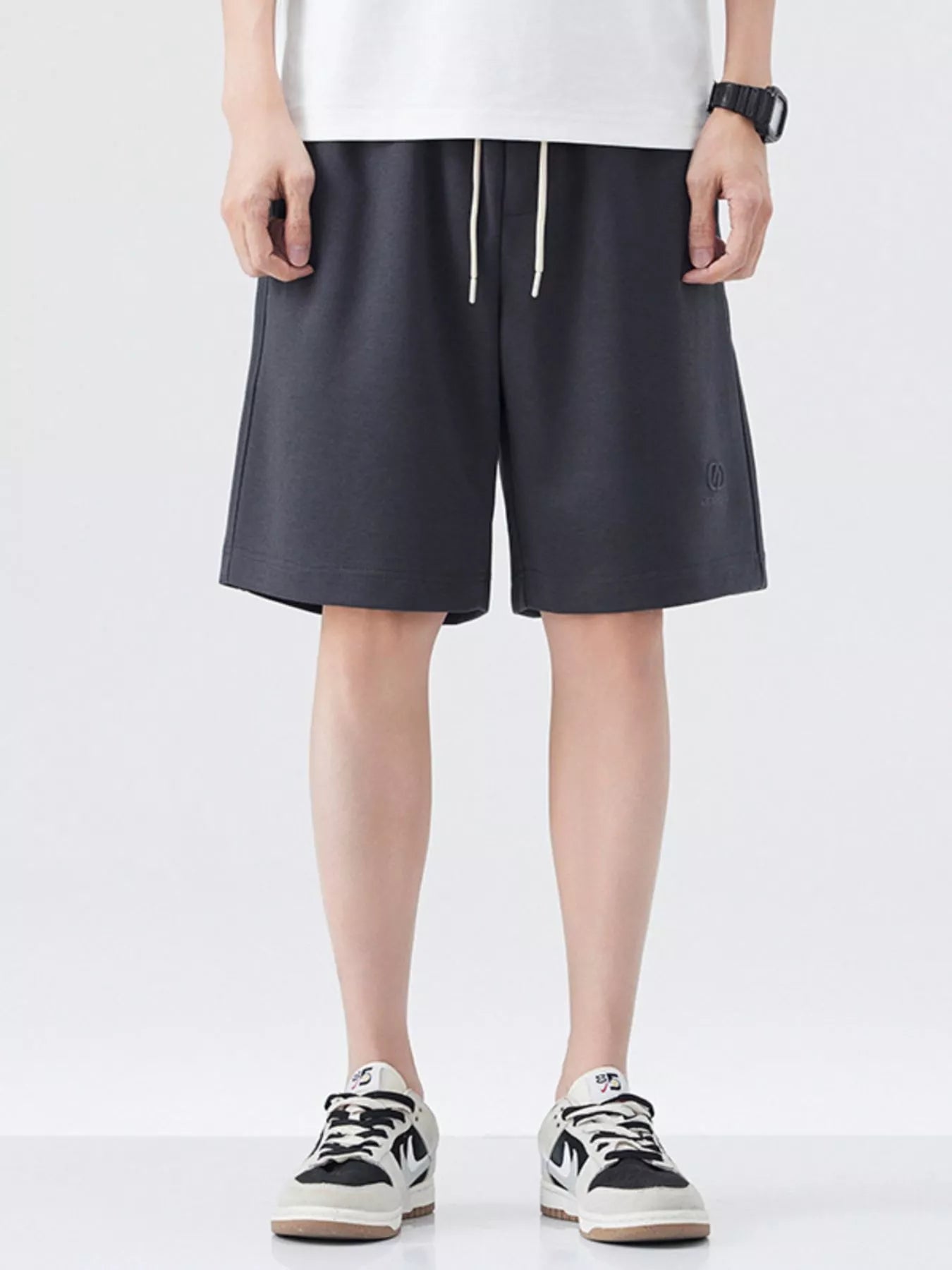Dark gray drawstring loose-fit shorts with front pockets and knee-length hem