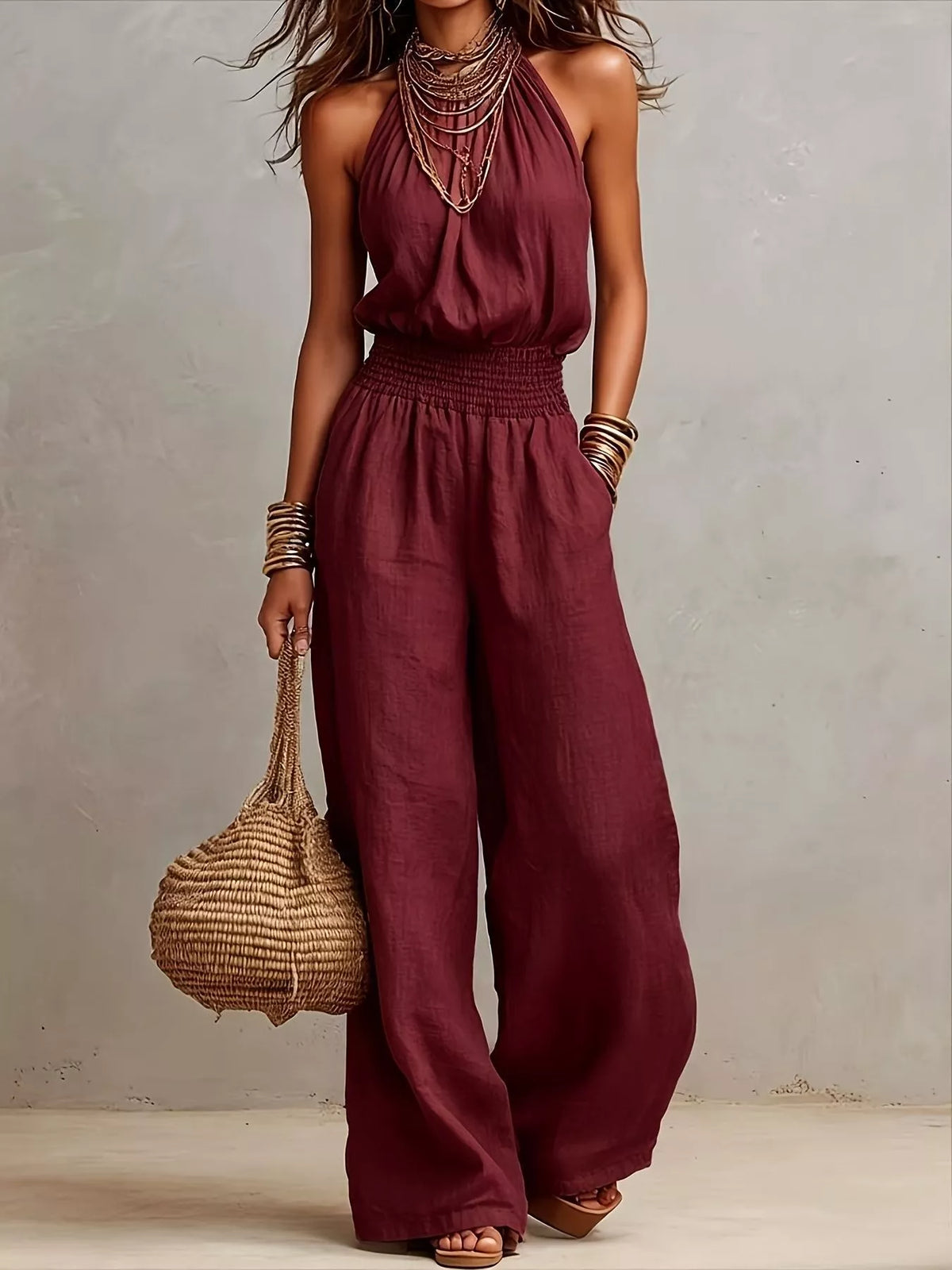 Burgundy smocked halter neck wide-leg jumpsuit with gathered waist and sleeveless fit.