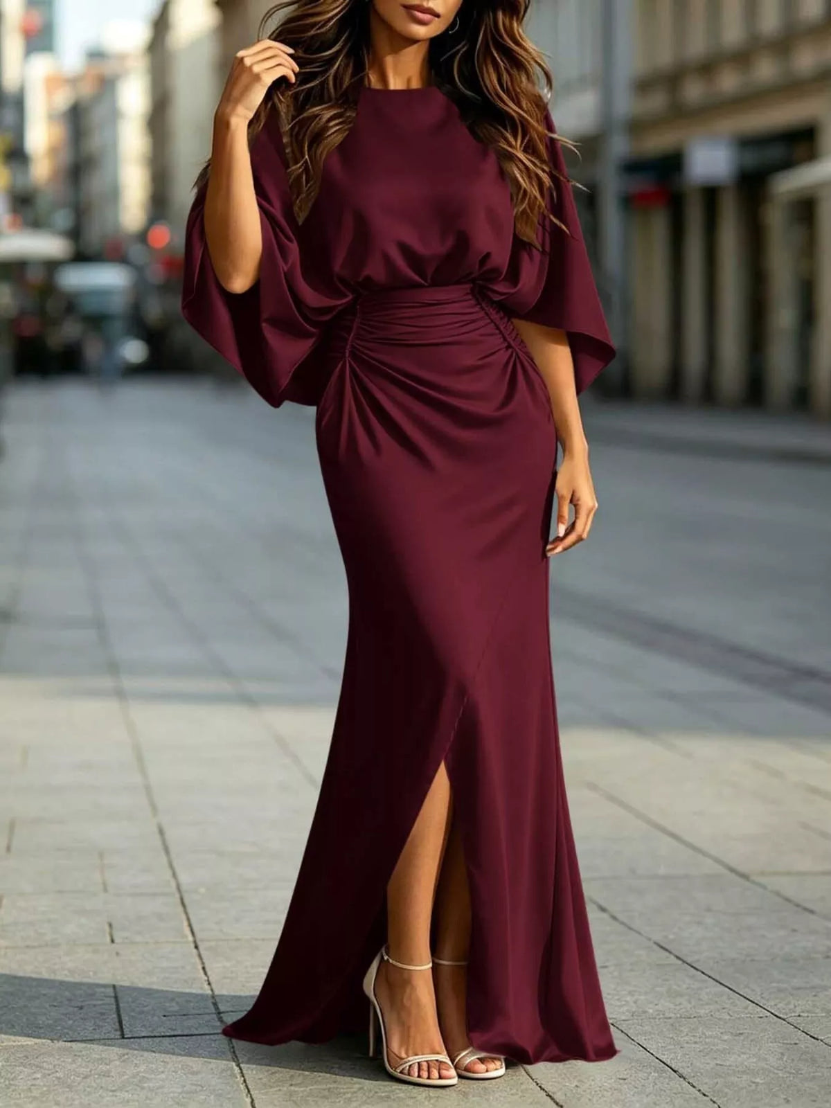 Burgundy satin maxi dress with ruched waist and draped sleeves; front slit