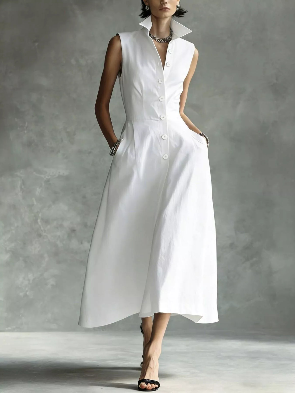 White sleeveless midi shirt dress with pointed collar and button front, A-line silhouette.