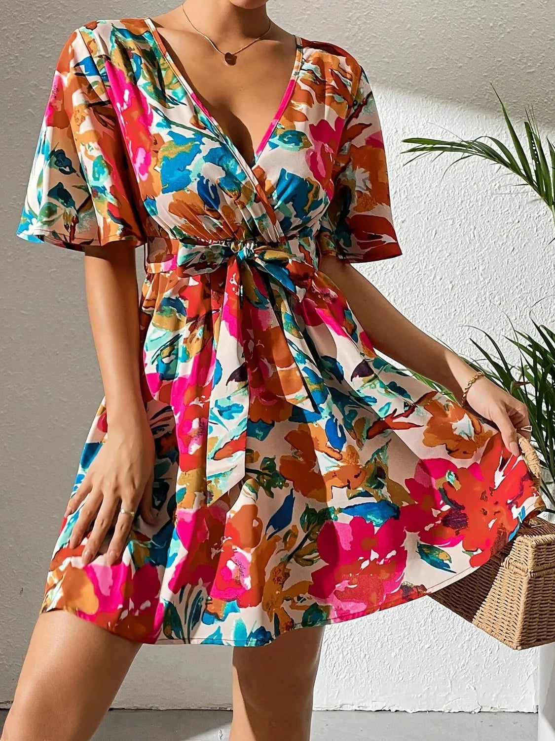 Printed surplice short-sleeve mini dress in vibrant multicolor floral pattern with front waist tie