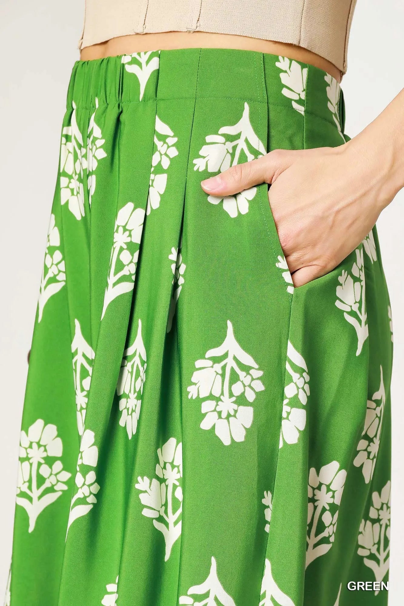 Green pleated wide-leg pants with white floral print and lace-trimmed waistband