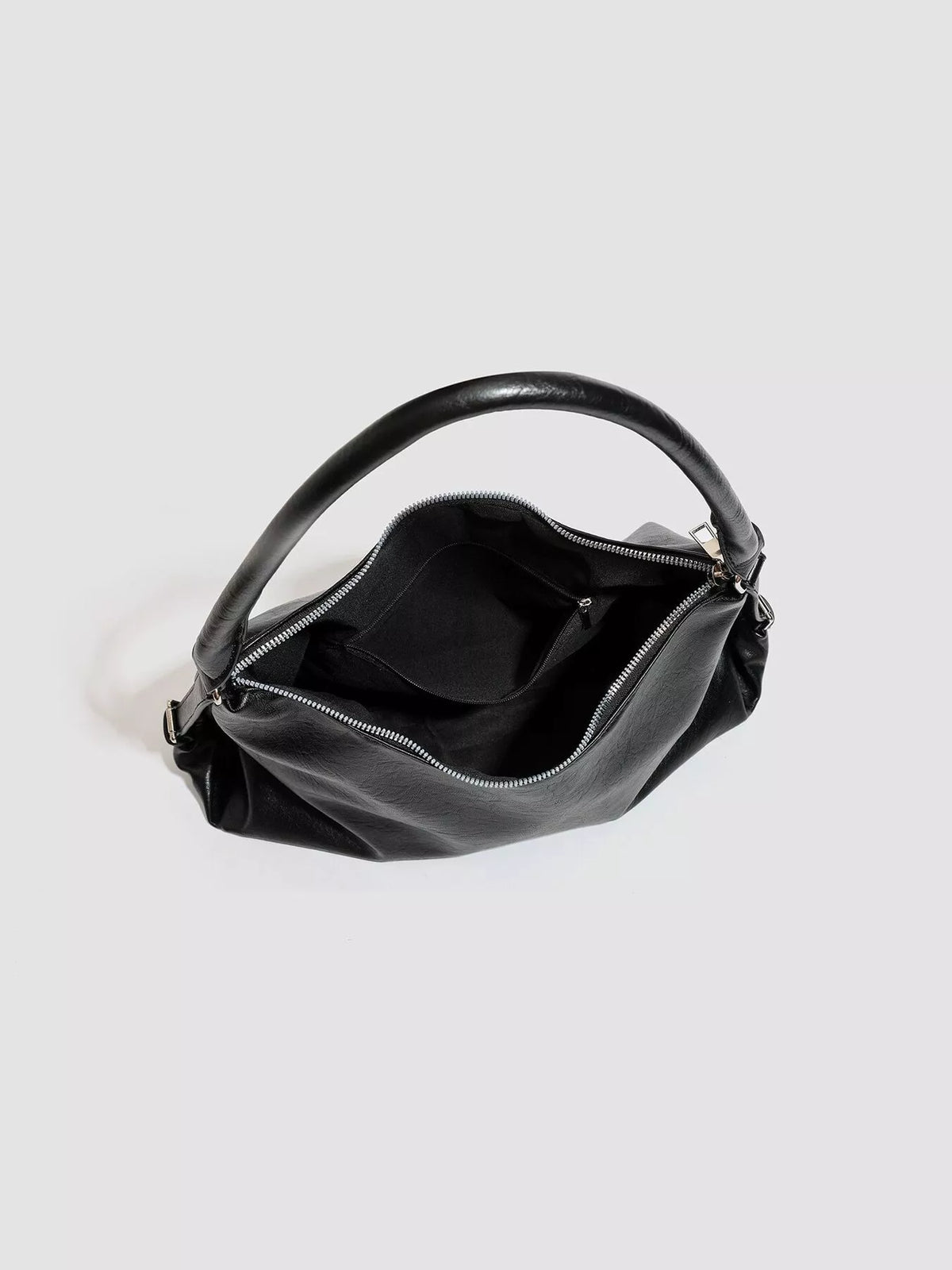 Black shoulder bag interior with zip pocket and fabric lining under curved handle