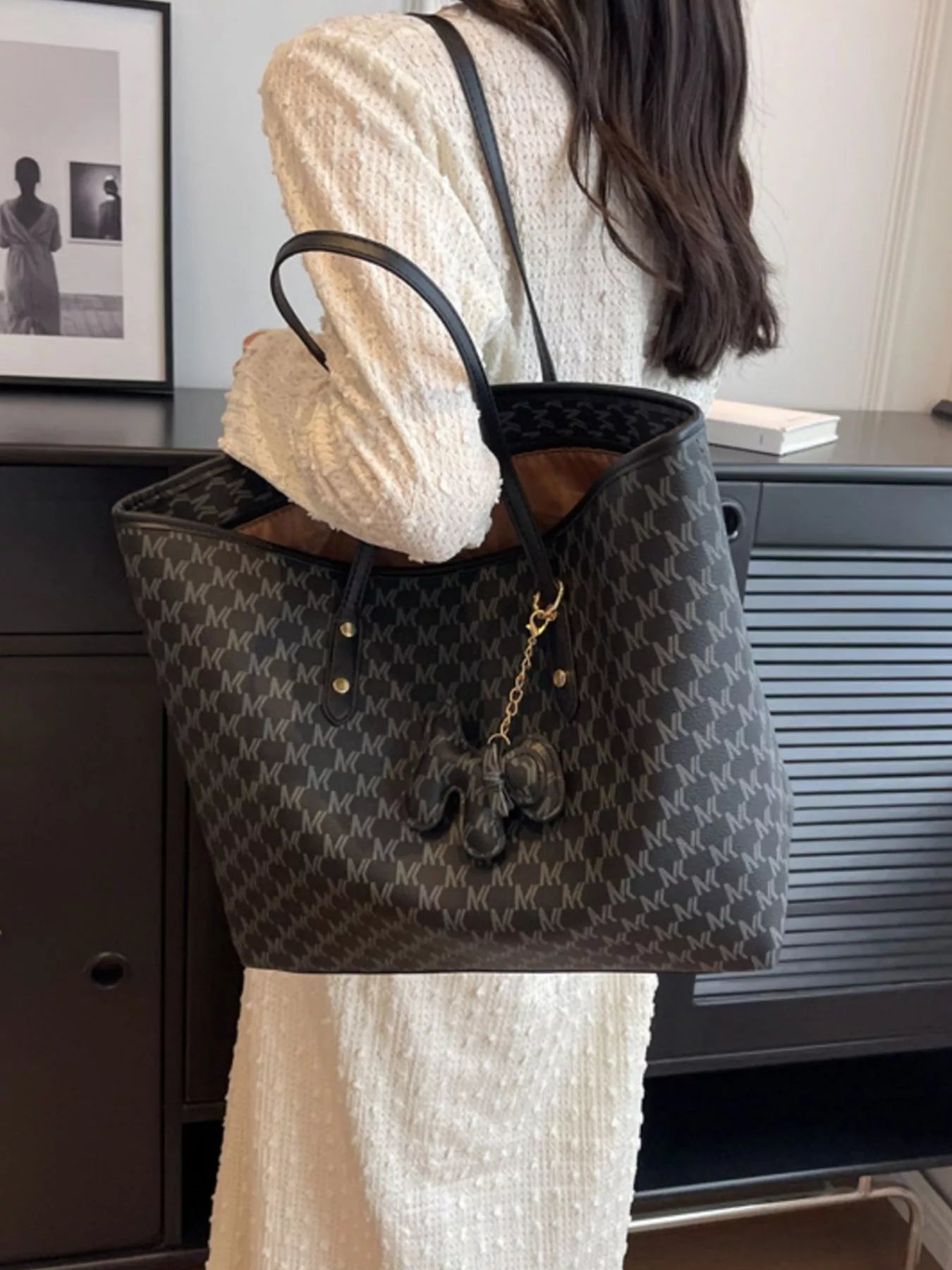 Dark monogram vegan leather tote with top handles and gold chain tassel charm