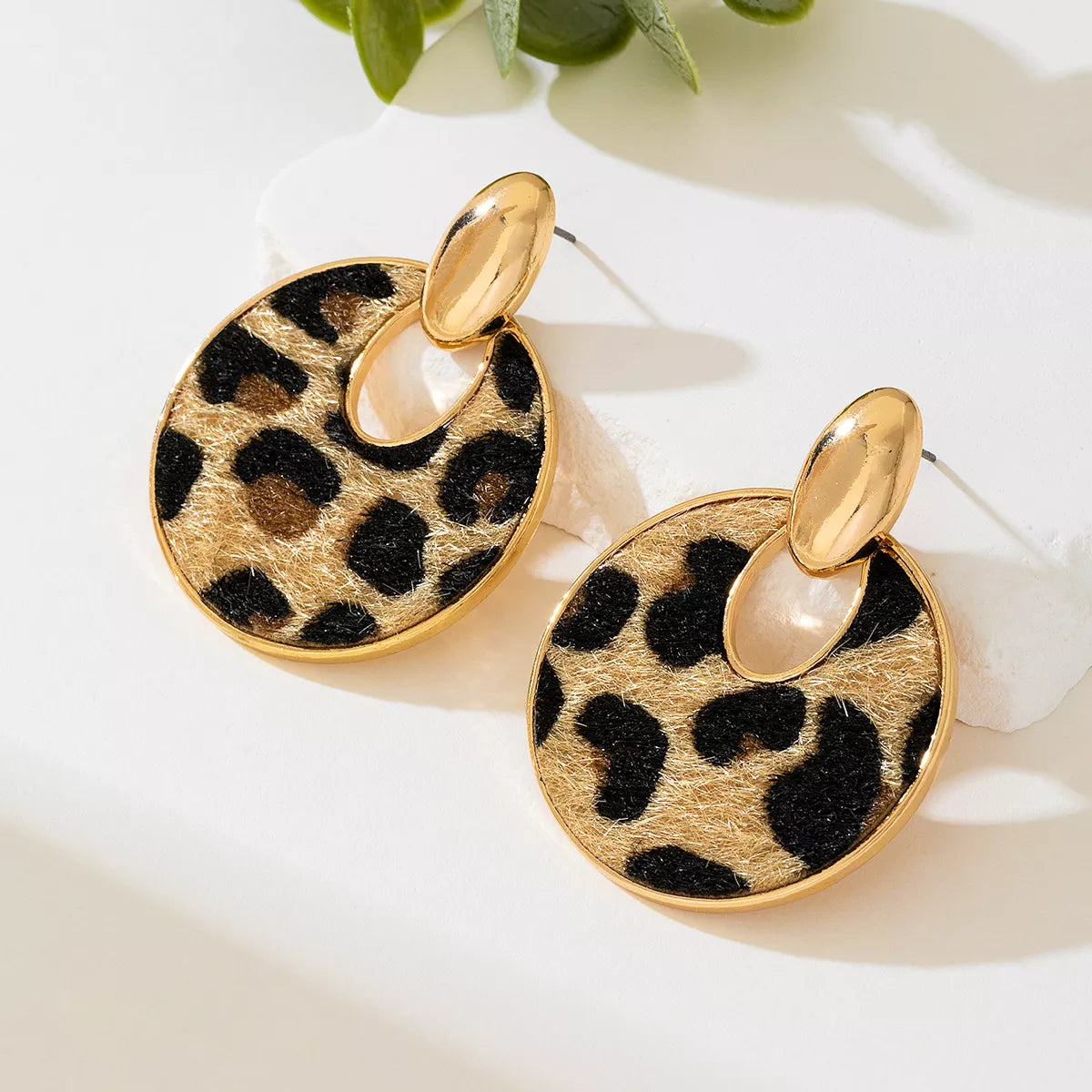 Leopard print circle dangle earrings with gold-tone top loops, angled view