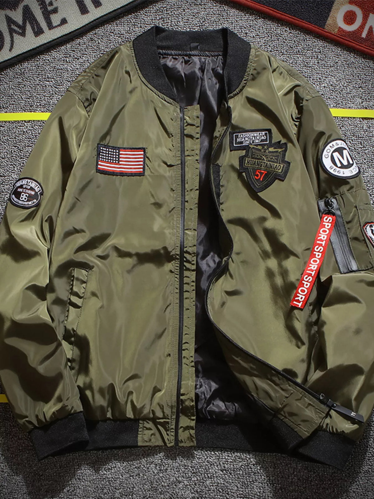 Men's olive green bomber jacket with front zipper and embroidered patches