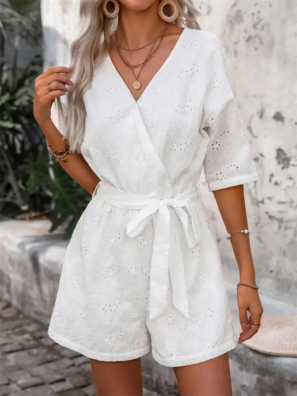 White eyelet romper with V-neck and bow-tied waist belt