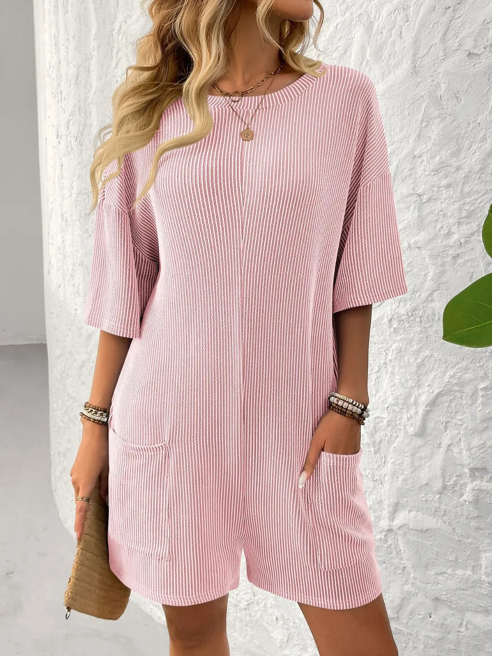 Textured pink romper with round neckline, half sleeves, and front pockets
