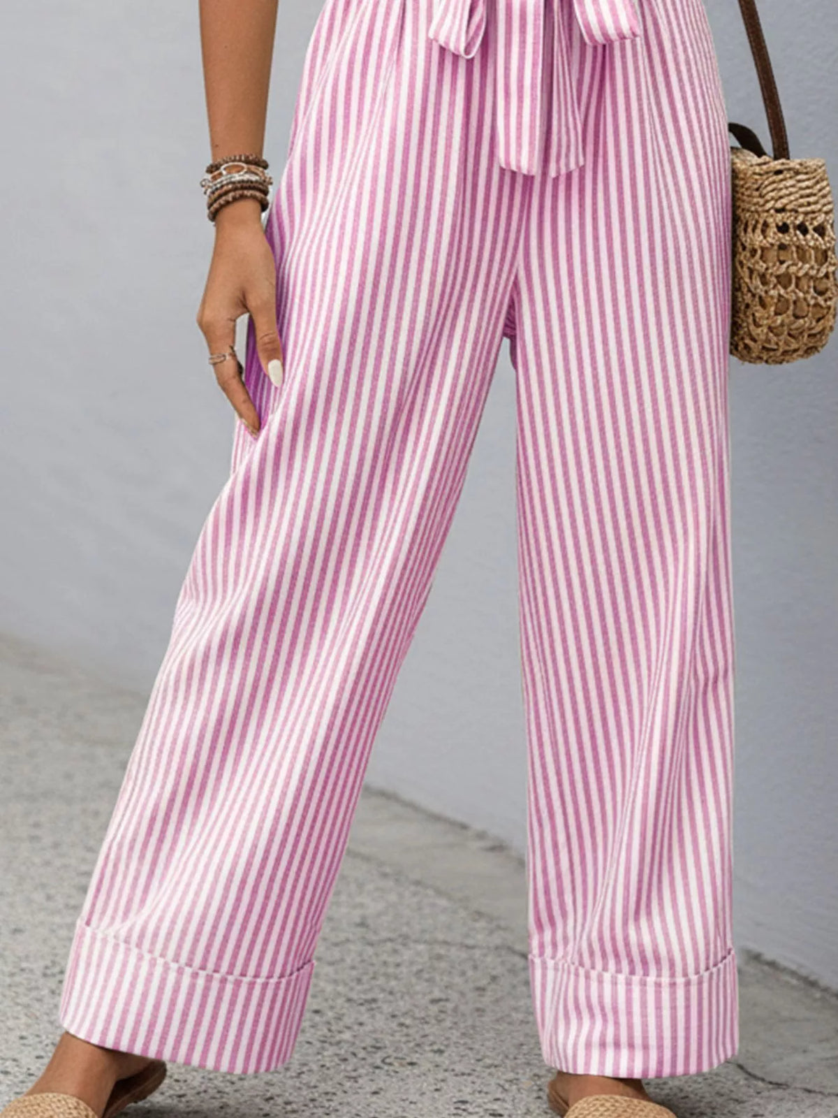 Pink striped sleeveless jumpsuit with V-neck, button front, and tied waist belt