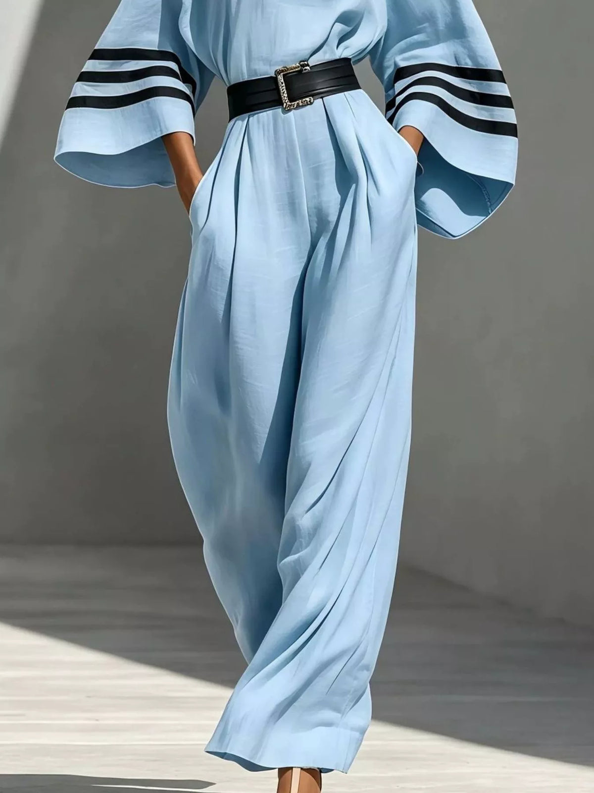 Light blue wide-sleeve jumpsuit with striped cuffs and belted waist, draped legs