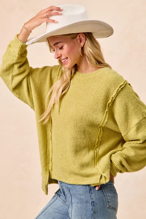 Lime green knit sweater with ribbed crew neck, long sleeves, uneven hem