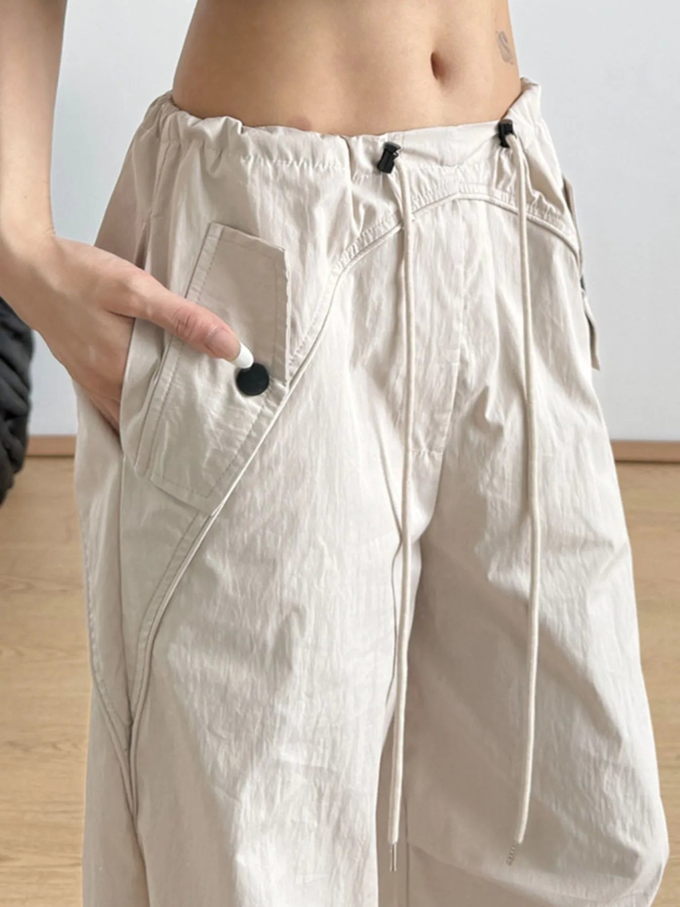 Beige wide-leg drawstring pants with adjustable ties and side pocket details
