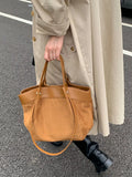 Brown suede shoulder bag with tan leather handles and stitched seams