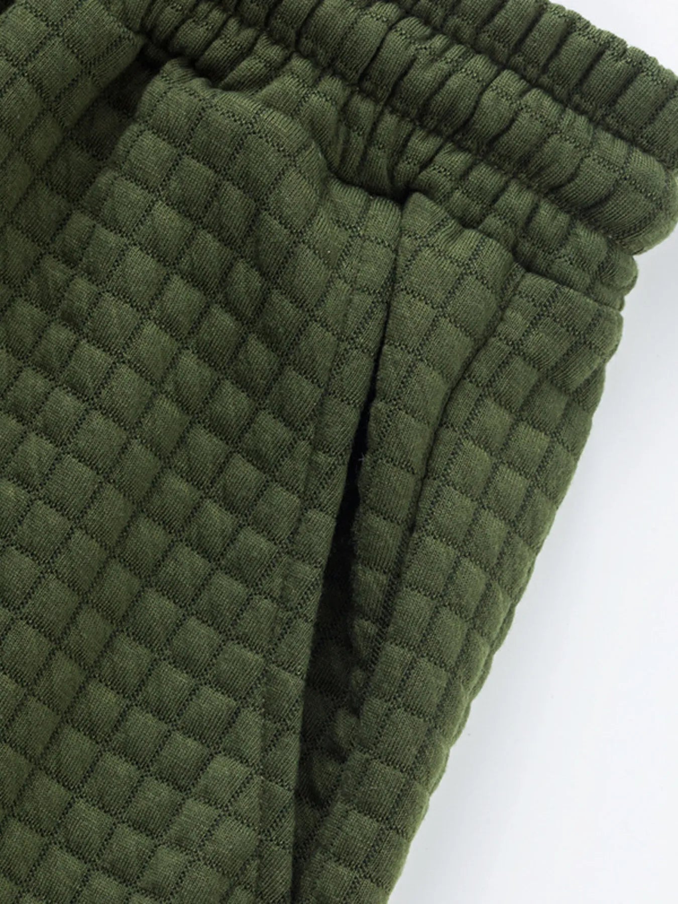 Dark green drawstring waistband and elastic cuff on textured shorts