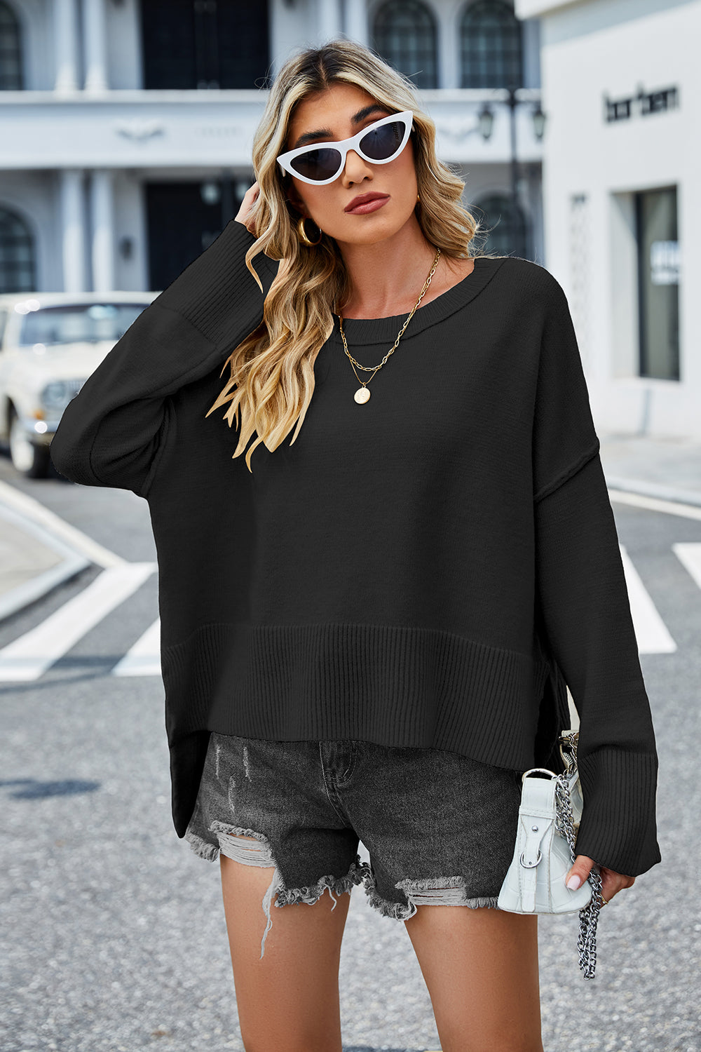 Black round-neck sweater with dropped shoulders, ribbed hem, and slit sides