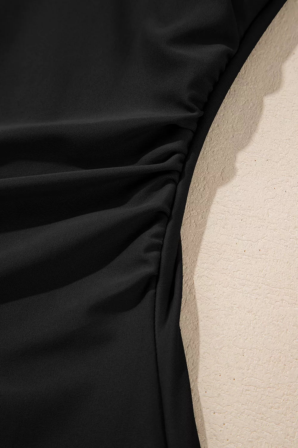 Black fabric ruching detail on a one-piece swimsuit