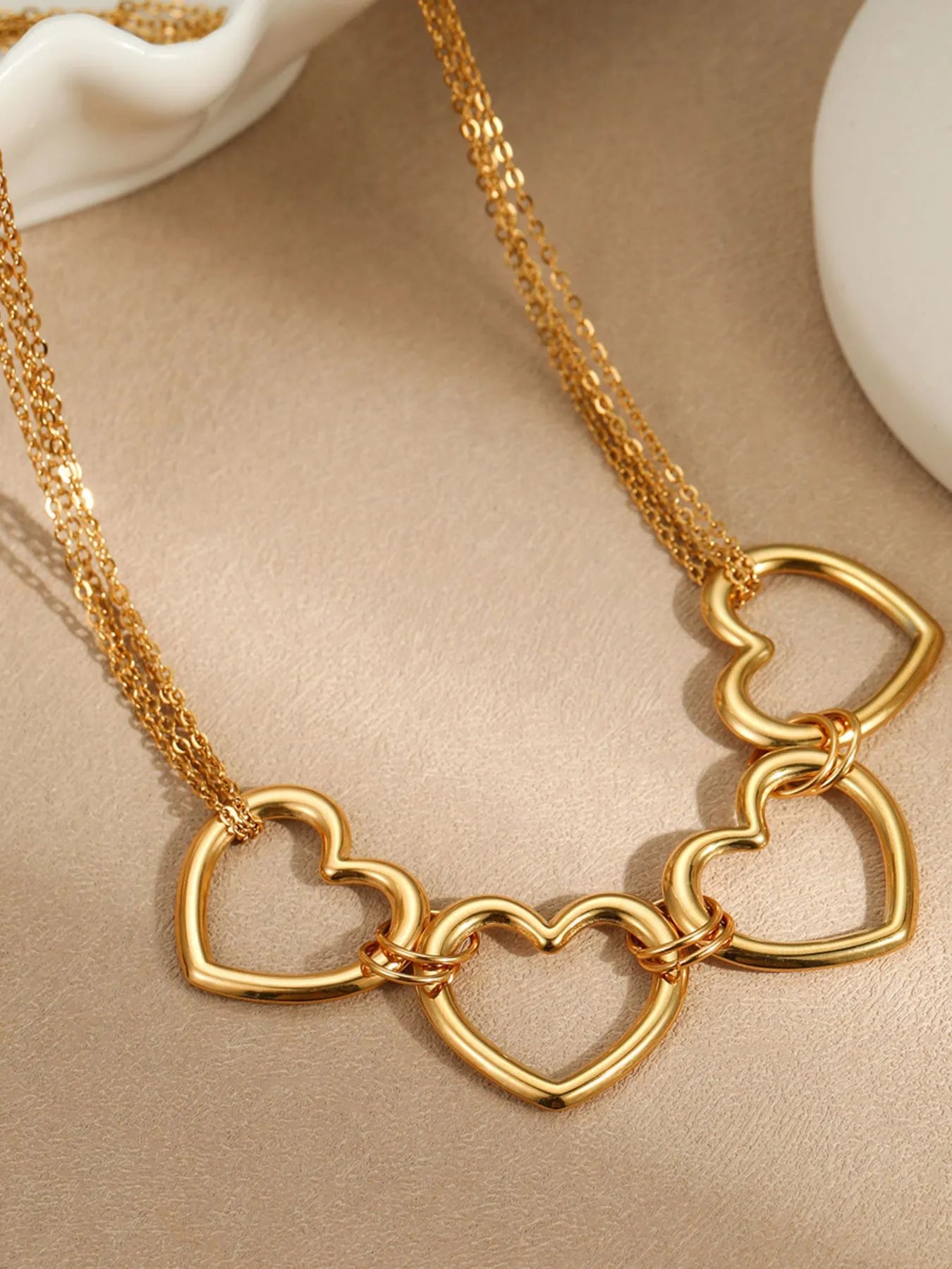 Gold-plated heart link necklace detail with interlocking heart charms